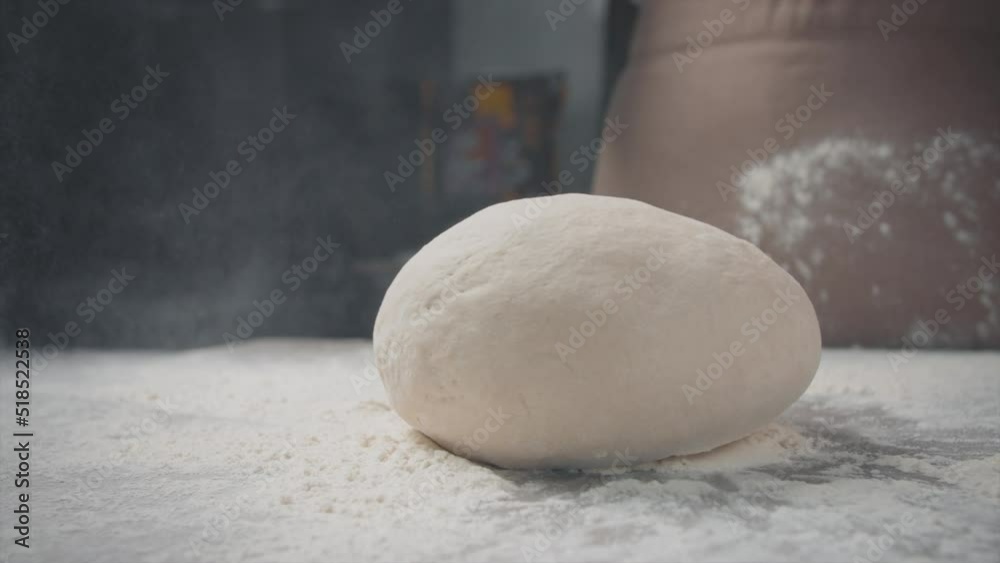 The dough falls on the table. Flour spreads. Close-up. The dough falls on the table. Flour spreads. Close-up.