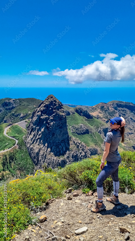 Woman with scenic view on mountain road next to volcanic rock formation Roque de Agando in Garajonay National Park on La Gomera, Canary Islands, Spain,Europe. Seen from lookout Mirador Morro de Agando