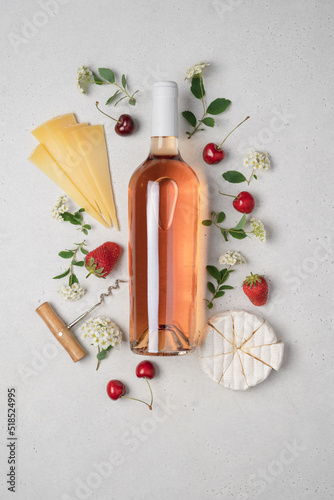 Bottle of rose wine with berries, fruits and cheeses on white background. Summer dry wine for picnic, party and good mood