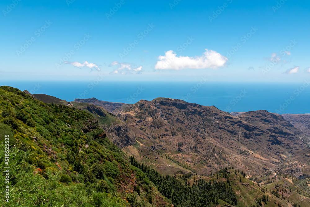 Valley Vallehermoso and hills in Garajonay National Park seen from Roque de Agando, La Gomera, Canary Islands, Spain, Europe. Hiking trail over hills covered by forest and tropical fauna in summer