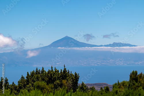 Scenic view on cloud covered volcano mountain peak Pico del Teide on Tenerife seen from Mirador Morro de Agando, La Gomera, Canary Islands, Spain, Europe. Lookout near Roque de Agando. Atlantic Ocean