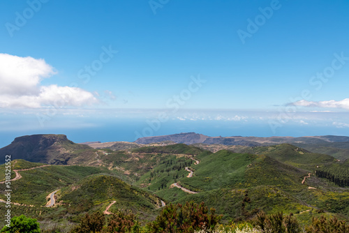 Panoramic view on massive volcanic plug Fortaleza de Chipude overlooking western coast of La Gomera, Canary Islands, Spain, Europe. Atlantic Ocean in background. Hilly mountain road to Valle Gran Rey
