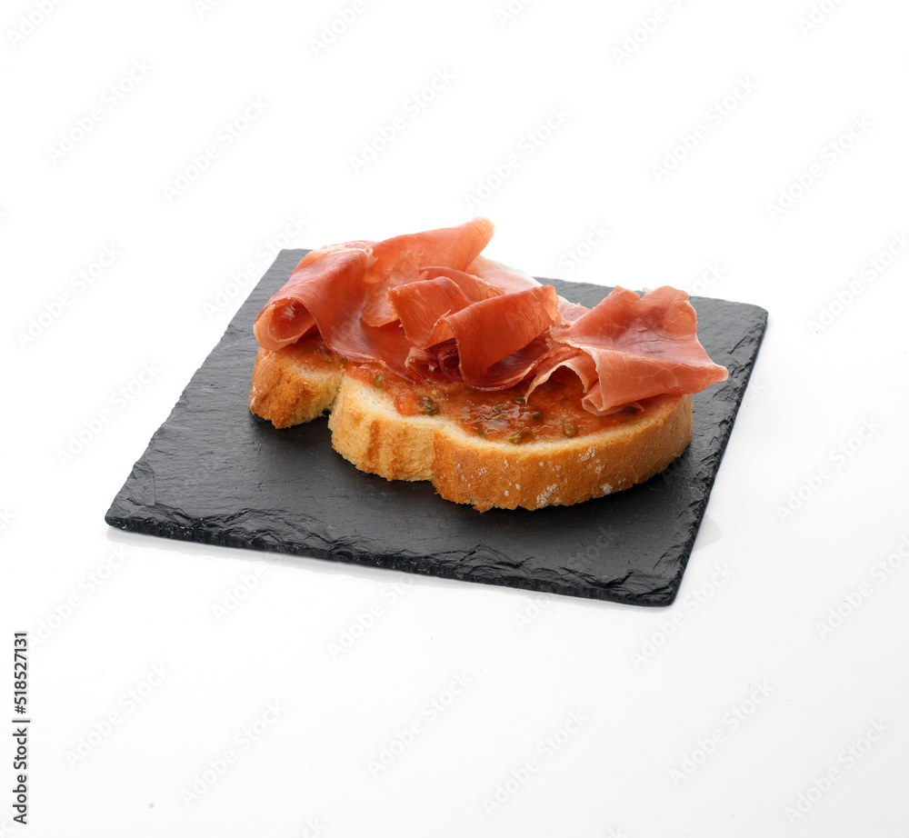tostada de jamón serrano con tomate sobre plato de pizarra. tapa española tostada de jamón serrano con tomate sobre plato de pizarra. tapa española