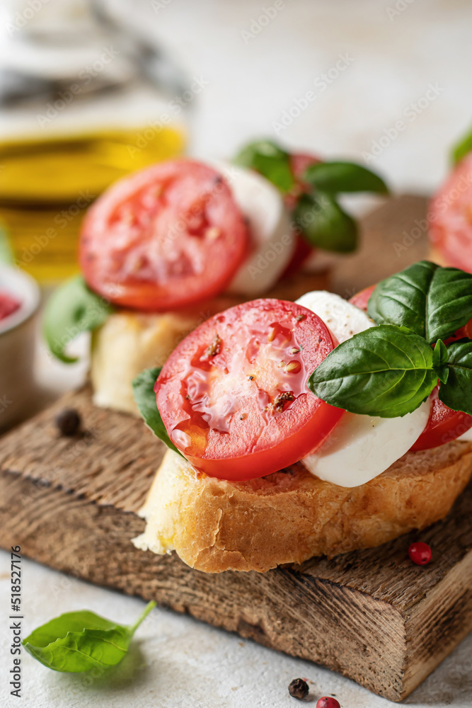 Bruschetta with tomatoes, mozzarella and basil on rustic wooden board close up with ingredients