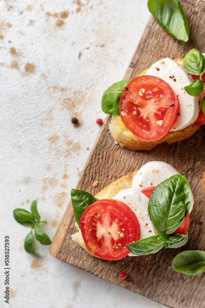 Italian bruschetta with tomatoes, mozzarella and basil on rustic wooden board close up. Top view, text space Italian bruschetta with tomatoes, mozzarella and basil on rustic wooden board close up. Top view, text space