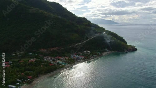 Beautiful aerial side drone shot of calm sea by the seashore, mountain side , cloudy sky and turquoise sea water photo