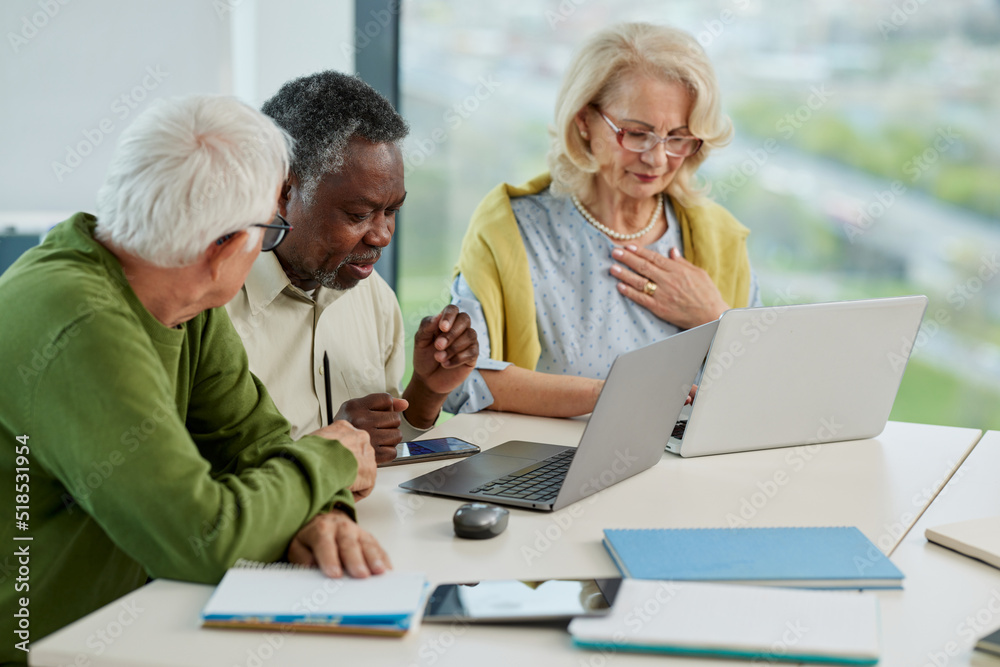 A multicultural group of senior students is doing an assignment on laptops in the classroom. A multicultural group of senior students is doing an assignment on laptops in the classroom.