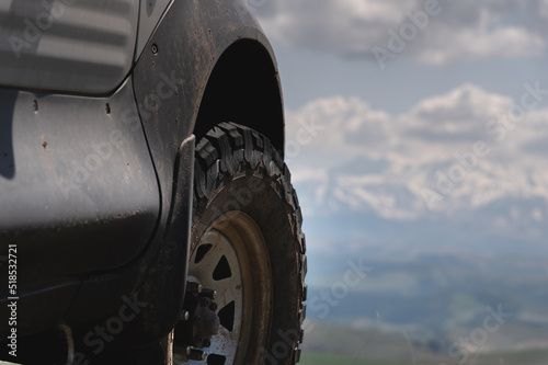 SUV wheel on the off-road adventure trail against the backdrop of mountains in the clouds