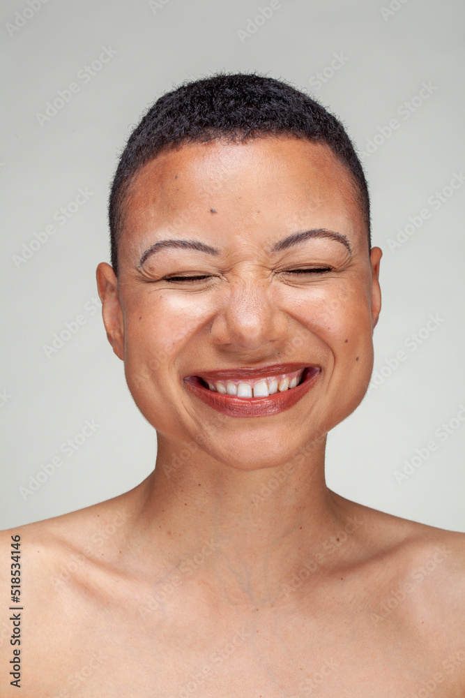 Studio portrait of shirtless woman laughing with eyes closed
