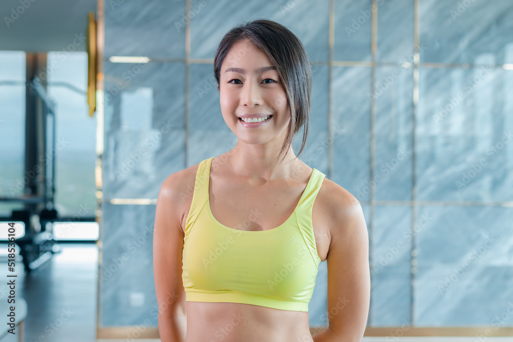 Beautiful smiling confident young Asian sport woman pretty face looking at camera posing happiness exercise at fitness gym