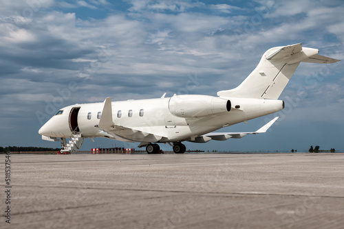 Modern white private jet with an opened gangway door at the airport apron photo