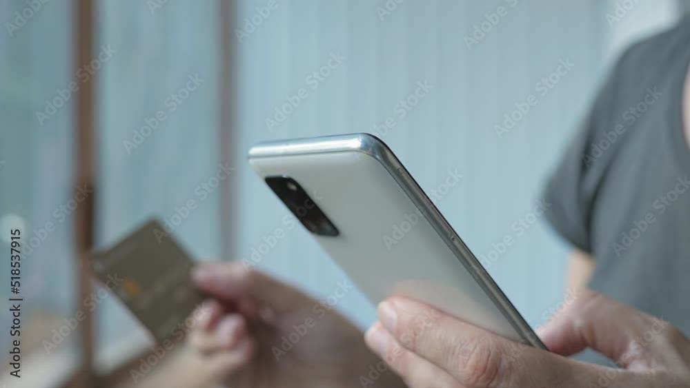 The girl makes a purchase using the phone. Buying on the Internet. Women's hands close up. The girl buys things by phone standing on the balcony, veranda. The girl makes a purchase using the phone. Buying on the Internet. Women's hands close up. The girl buys things by phone standing on the balcony, veranda.