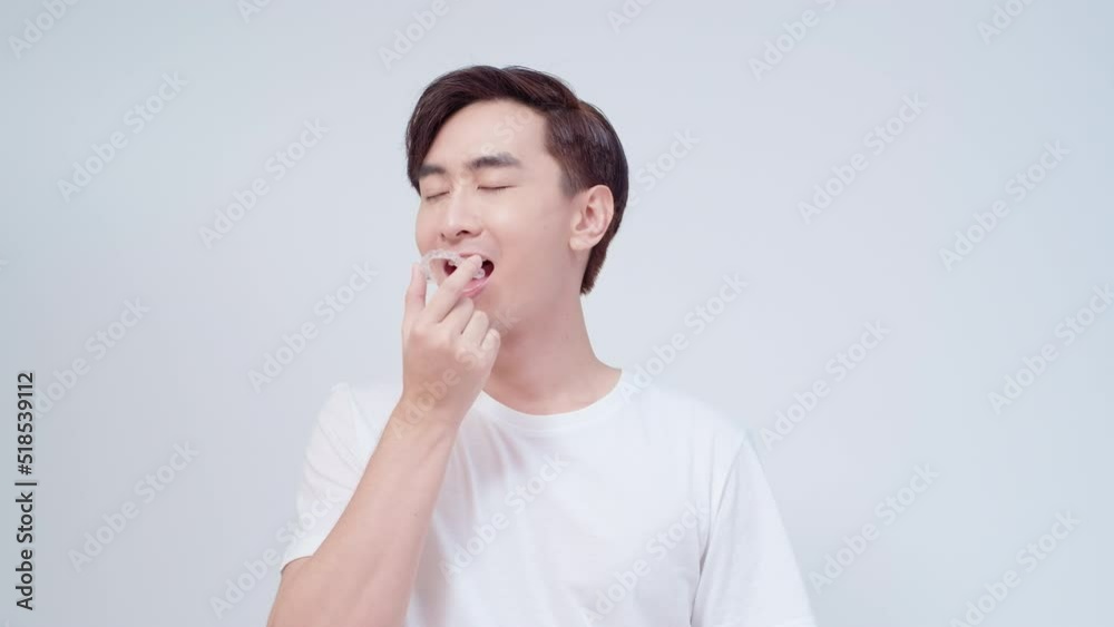 Young smiling man holding invisalign braces over white background studio, dental healthcare and Orthodontic concept Young smiling man holding invisalign braces over white background studio, dental healthcare and Orthodontic concept