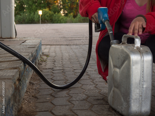 a girl pours gasoline into a metal canister from a pistol at a gas station photo