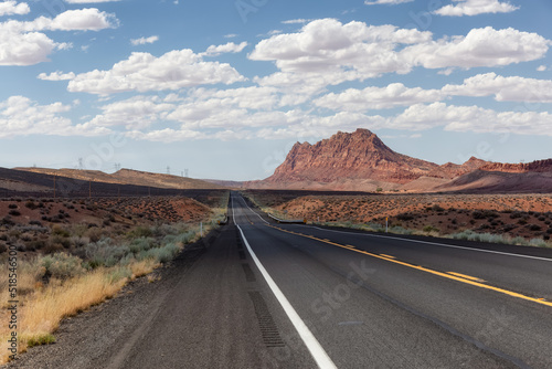 Scenic Road in the Dry Desert with Red Rocky Mountains in Background. Near Page, Arizona, United States of America. Adventure Travel