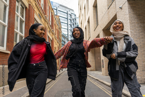 Three young women wearing hijabs walking in city