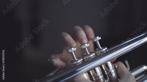 Fingers of a trumpet player playing a silver plated trumpet on the valves in slow motion