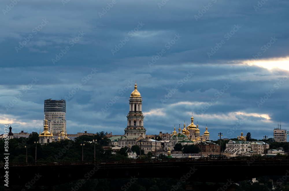 Picturesque view of famous green leaves Kyiv's hills with ancient Kyiv Pechersk Lavra. It is a historic Orthodox Christian monastery. Stormy sky and gloomy clouds. UNESCO World Heritage Site