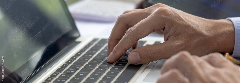 Businessman's hand presses on a laptop keyboard, Using computers to conduct financial transactions because the convenience and speed, World of technology and internet communication.