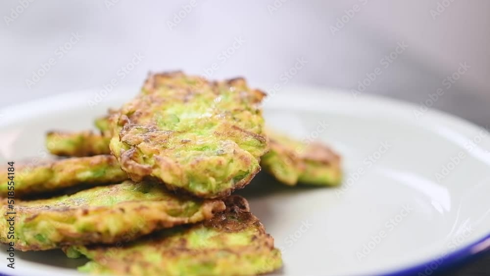 Chef serves a courgette fritters on a plate.
Chef serves a courgette fritters on a plate.