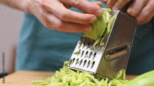 Grating fresh courgette with a grater in the kitchen.
 photo