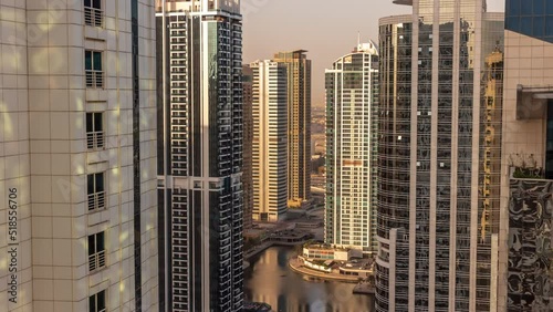 Tall residential buildings at JLT district aerial morning timelapse during sunrise, part of the Dubai multi commodities centre mixed-use district. Skyscrapers with long shadows photo
