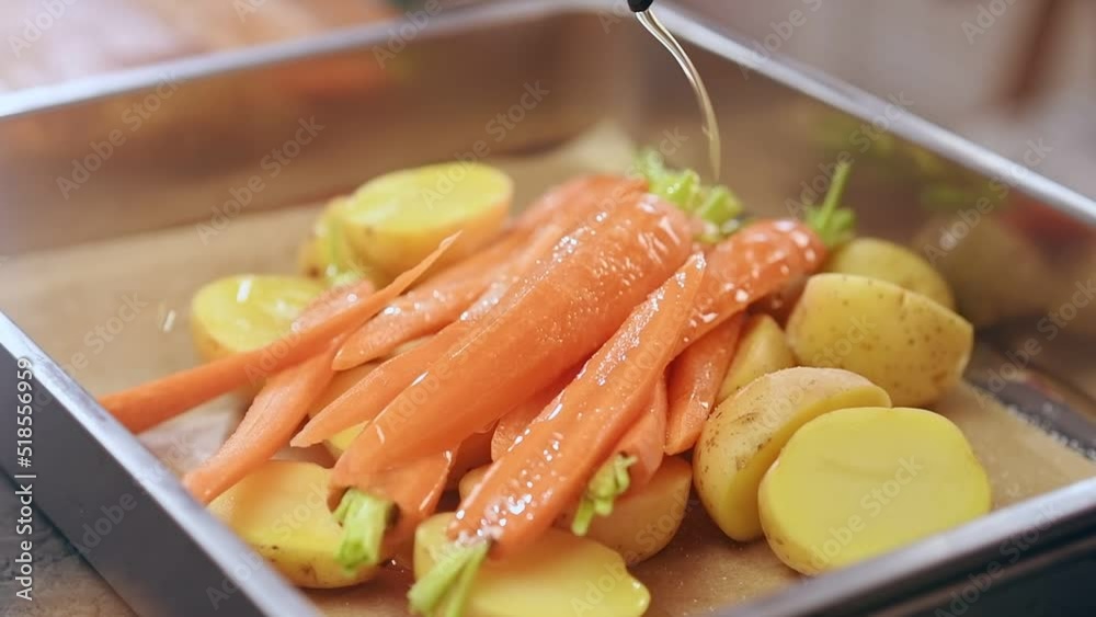 Chef pouring olive oil on carrots and potatoes, before baking.
Chef pouring olive oil on carrots and potatoes, before baking.