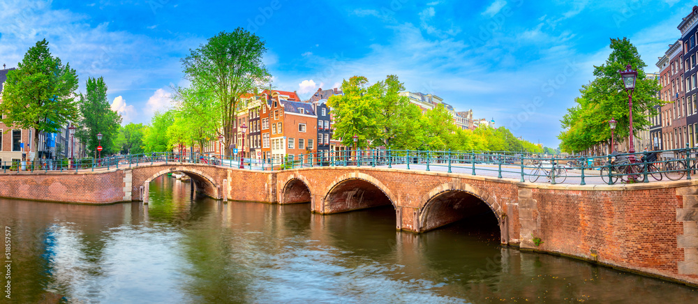 Famous view of heart of Amsterdam. Beautiful day, blue sky, old sloping houses, bridges and canals. Panoramic Amsterdam