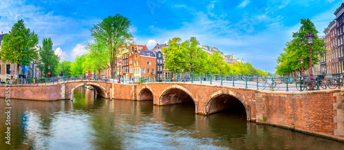 Famous view of  heart of Amsterdam. Beautiful day, blue sky, old sloping houses, bridges and canals. Panoramic Amsterdam