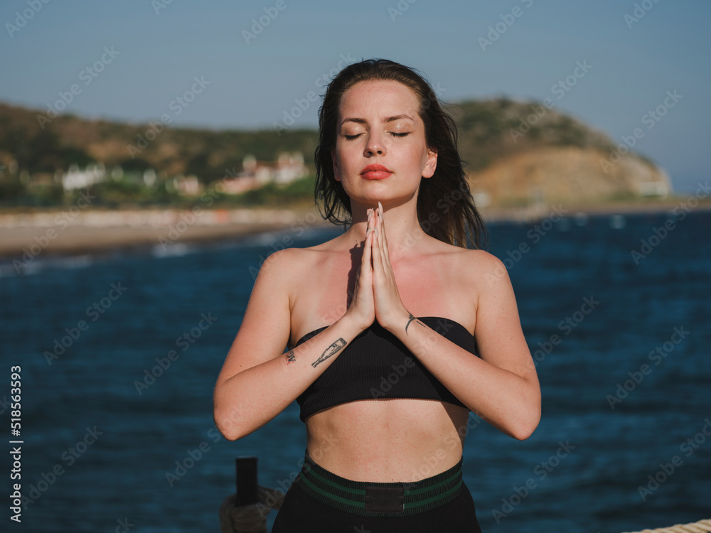 young woman doing yoga on the beach