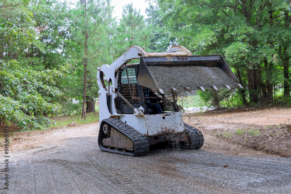 An old road reconstruction project requires the use of bobcat tractor to move and unload gravel
