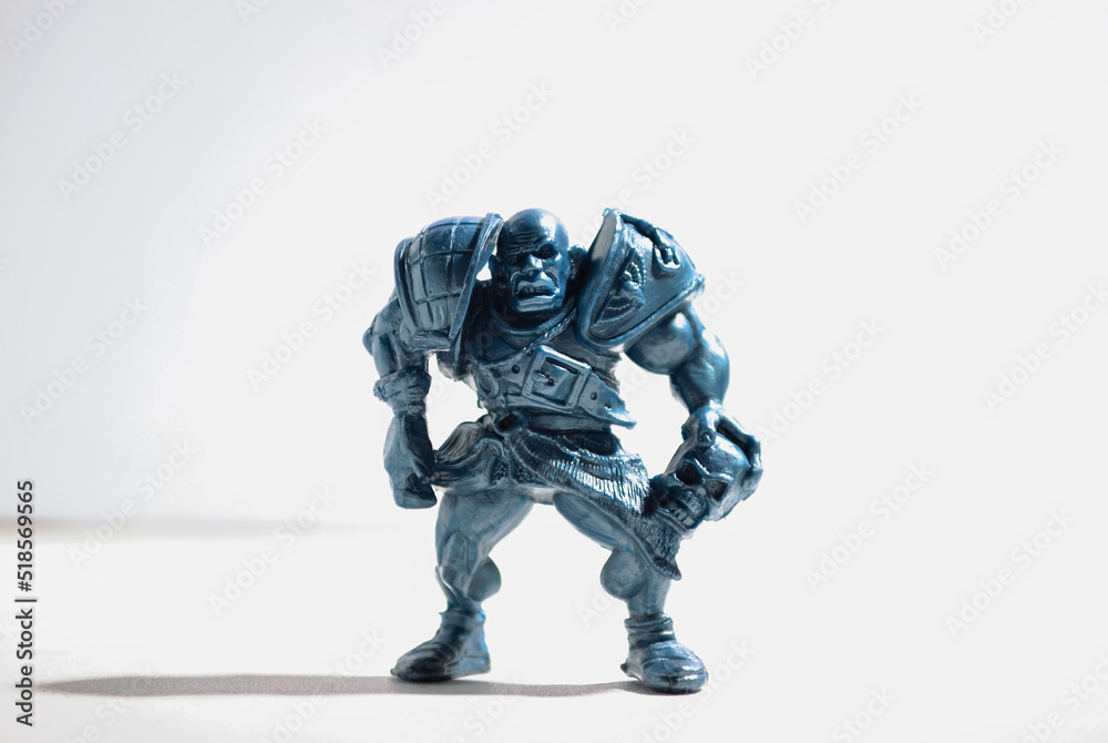 A figurine of an aggressive and vicious bald warrior in armor with a skull stands on a white background A figurine of an aggressive and vicious bald warrior in armor with a skull stands on a white background