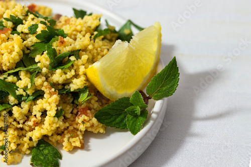 Close up of tabule salad with bulgur and vegetables decorated with mint and lemin i photo