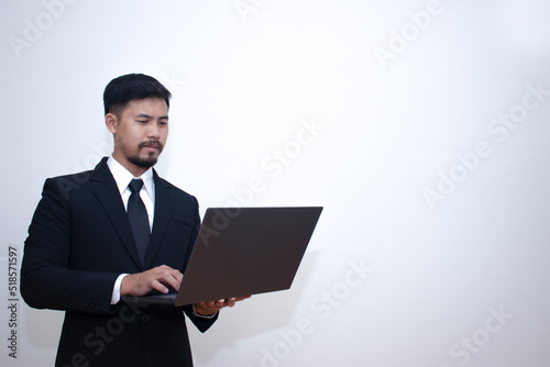 A young businessman in a shirt presses on the keyboard on his laptop with a serious expression. dissatisfied with the current state of finance, work, Isolated on gray background. Empty space for text.
