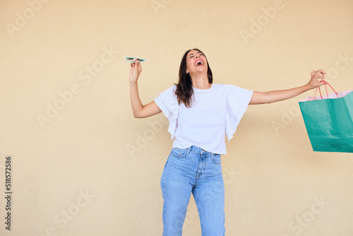 happy young woman enjoying a day of shopping with a bag in one hand and sunglasses in the other.