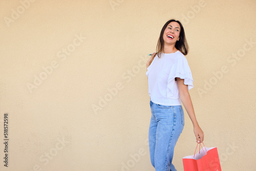 happy young woman enjoying a day of shopping with a bag in one hand and sunglasses in the other.