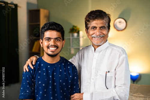 Portrait shot of happy smiling caring Grandfather with grandchild at home looking camera - concept of support, wellbeing and wisdom