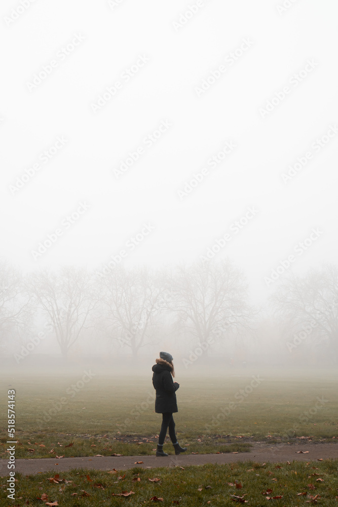 Woman walking in a London park on a foggy morning Woman walking in a London park on a foggy morning