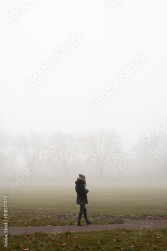 Woman walking in a London park on a foggy morning