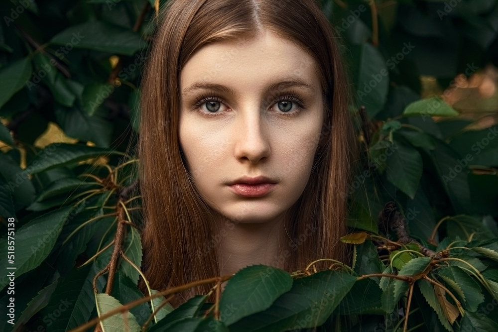 Eva in the eden garden portrait of a beautiful fair haired girl in the leaves of a tree in the summer in nature with serious looking Eva in the eden garden portrait of a beautiful fair haired girl in the leaves of a tree in the summer in nature with serious looking