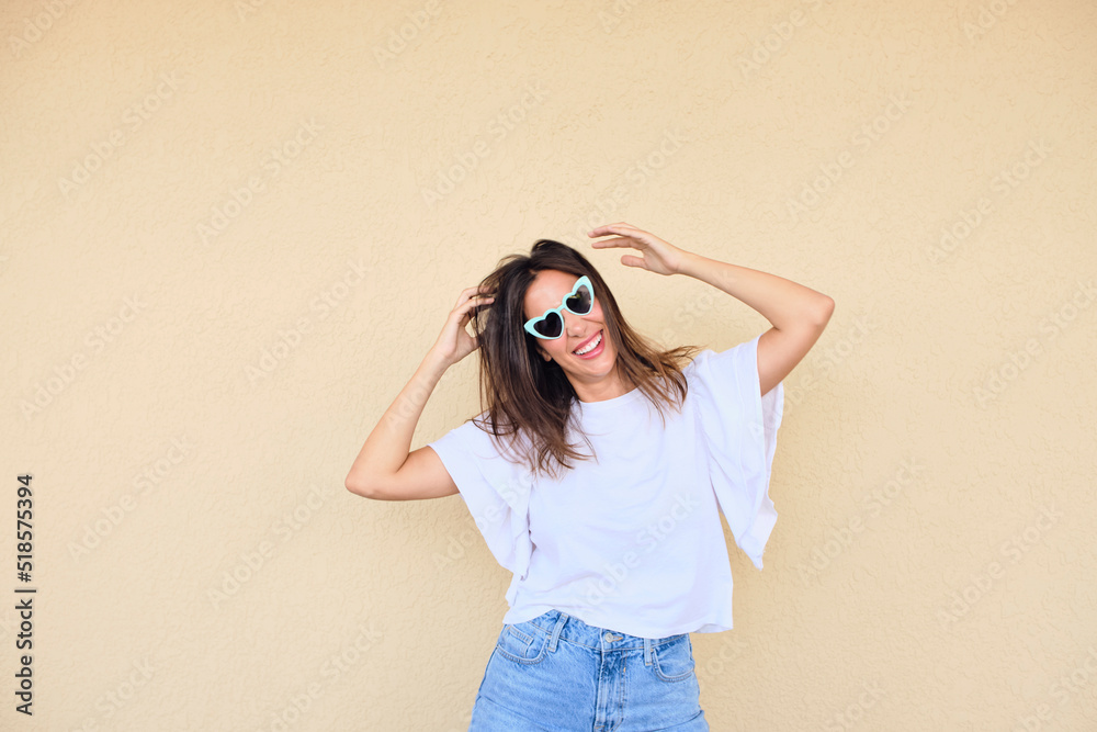 happy young woman posing in a fun way with heart shaped sunglasses 