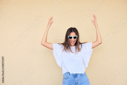 happy young woman posing in a fun way with heart shaped sunglasses 