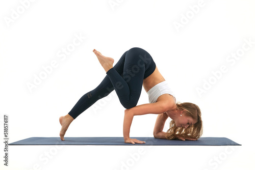 young slim caucasian woman in sportswear performs eka pada bakasana yoga pose photo