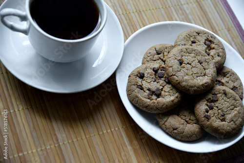 Tea pair and oatmeal cookies with chocolate on a mat. Delicious breakfast with tea and sweet cookies.