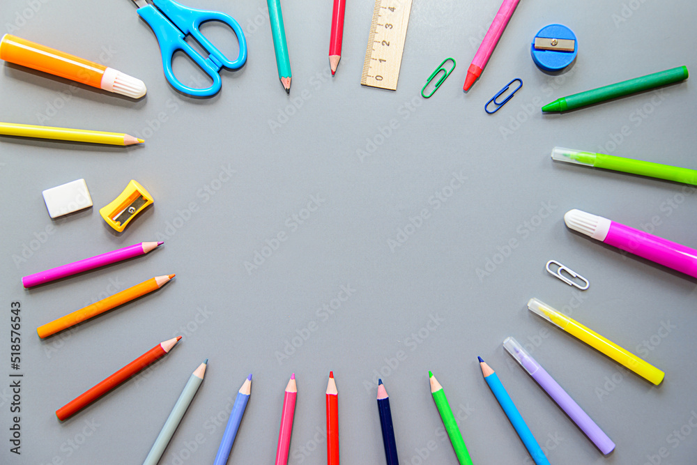 school supplies on a gray background. Colored pencils, felt-tip pens, eraser, paper clip, scissors, sharpener. Back to school. school items arranged in a circle school supplies on a gray background. Colored pencils, felt-tip pens, eraser, paper clip, scissors, sharpener. Back to school. school items arranged in a circle