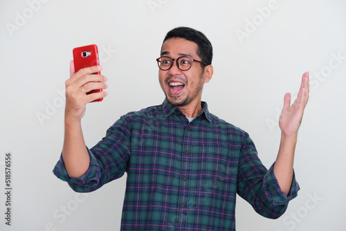 Adult Asian man looking to his handphone with happy expression photo