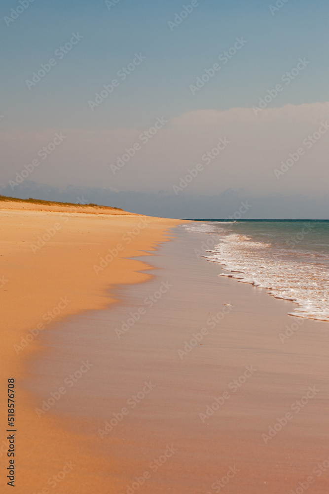 A paradise beach with the turquoise sea. A pristine sandy beach with a dune, pristine sand, emerald sea.
