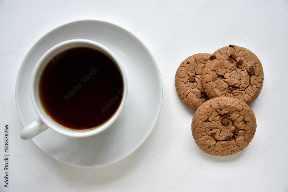Tea pair and oatmeal cookies with chocolate on a white background. Delicious lunch with tea and sweet cookies. Porcelain tea set with a hot drink. Tea pair and oatmeal cookies with chocolate on a white background. Delicious lunch with tea and sweet cookies. Porcelain tea set with a hot drink.