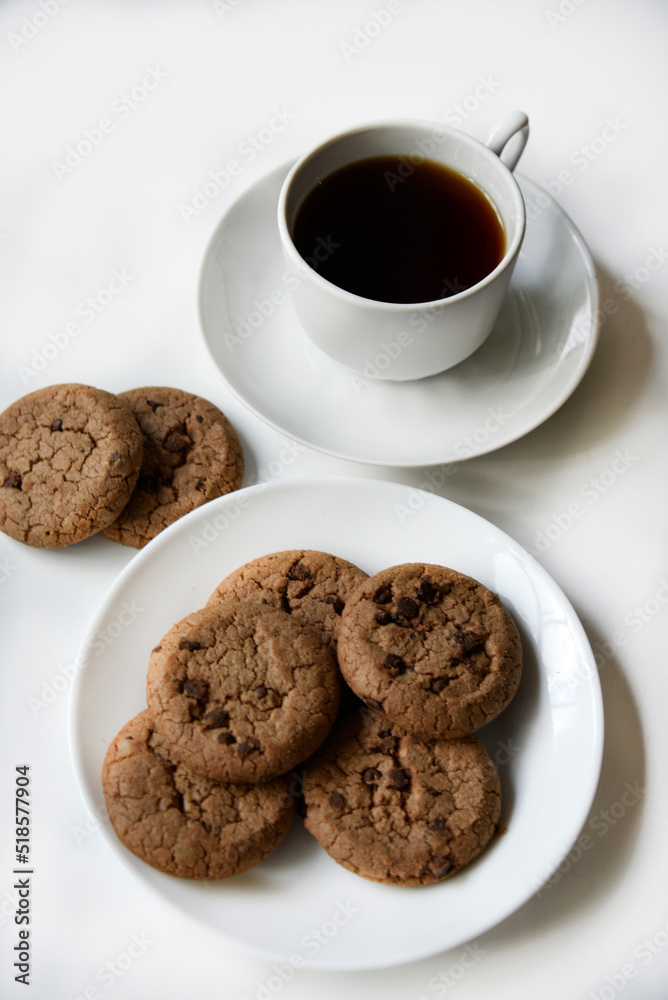 Tea pair and oatmeal cookies with chocolate on a white background. Delicious lunch with tea and sweet cookies. Porcelain tea set with a hot drink. Tea pair and oatmeal cookies with chocolate on a white background. Delicious lunch with tea and sweet cookies. Porcelain tea set with a hot drink.