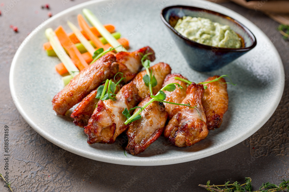 Buffalo chicken wings with sauce on plate on brown table macro close up Buffalo chicken wings with sauce on plate on brown table macro close up